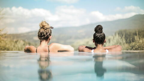 Two women looking out from an infinity pool