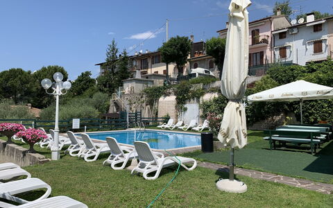 Garda 54: Sky, Plant, Cloud, Building, Furniture, Water, Umbrella, Outdoor Furniture, Tree, Chair
